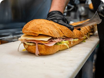 A large sandwich is being cut in half.