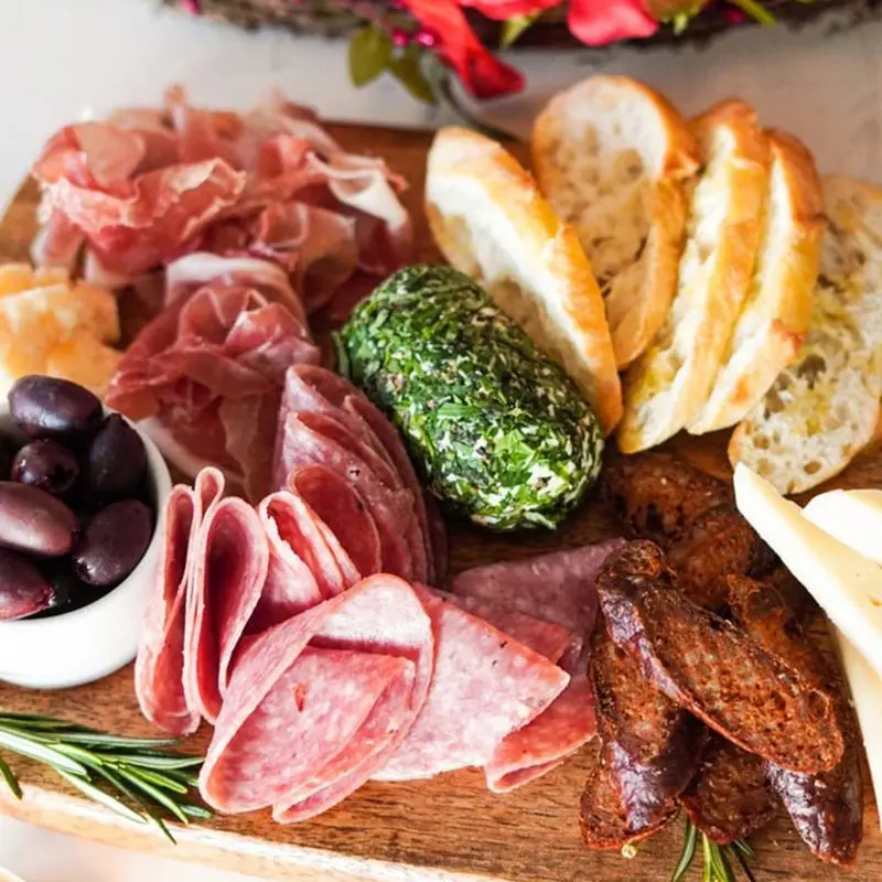 A wooden cutting board topped with meat and bread.