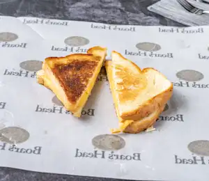 A grilled cheese sandwich cut in half on top of wax paper.