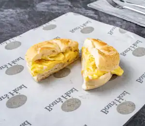 A half eaten egg sandwich sitting on top of a paper.