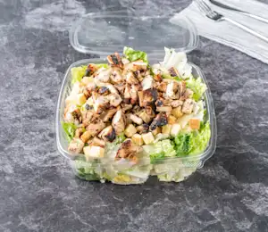 A salad in a plastic container on the table.