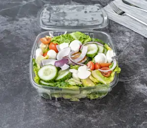 A salad in a plastic container on the table.