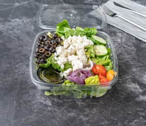 A salad in a plastic container on the table.